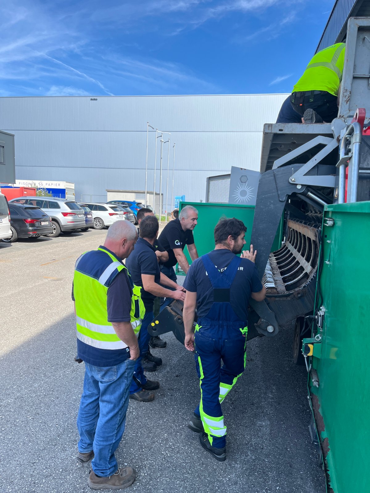 Servicetechniker demonstrieren bei Unterhaltsarbeiten an einer Maschine im Außenbereich lebenswichtige Regeln zur Arbeitssicherheit.